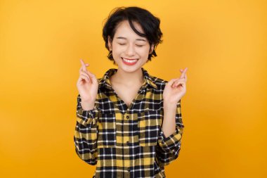 Güzel genç bir kadın parmaklarını çapraz yapar, kırmızı gömlek giyer, iyi şansa inanır, geniş bir şekilde gülümser. İnsanlar ve dilek kavramı