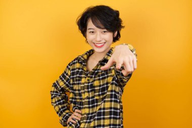 Genç ve güzel bir kadın kameraya bakıyor. Tatmin olmuş, kendine güvenen, dost canlısı bir gülümsemeyle. Düz duvara karşı seni seçiyor.