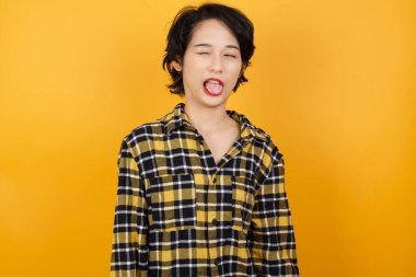 Güzel genç bir kadın komik bir ifadeyle dilini dışarı çıkartıyor. Duygu kavramı.