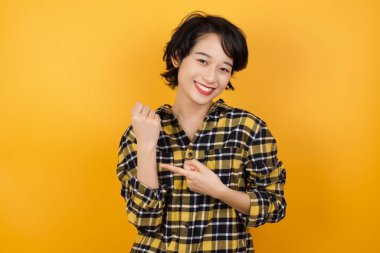 Güzel, genç bir kadın. Aceleyle kol saatini gösteriyor. Sabırsızlıkla kameraya bakıyor.