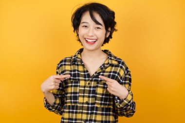 Neşeli ve şık bir kadının yatay pozu gündelik gömleği işaret ediyor.