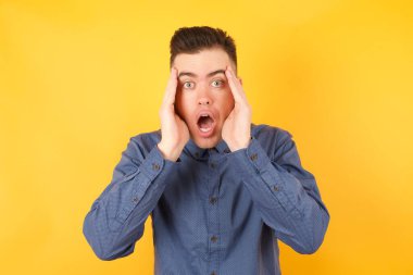 Yakışıklı genç işadamı, korkmuş bir ifadeyle, elleri başının üstünde, çenesi düşük 