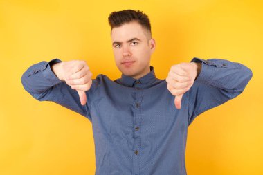 Yakışıklı genç iş adamı iki parmağını aşağıda tutarak üzülüyor. Konseptten nefret.