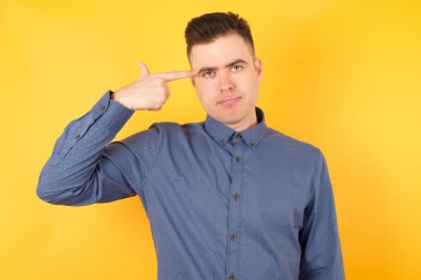 Yakışıklı genç iş adamı intihar jesti yapıyor, her şeyden bıkmış, sinagogda elle çekim yapıyor, stüdyo arka planında izole edilmiş..