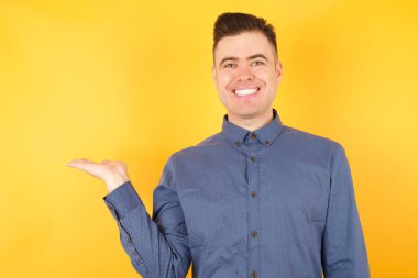 Yakışıklı genç işadamı, kameraya bakarak, elini uzatıyor ve onu gösteriyor..