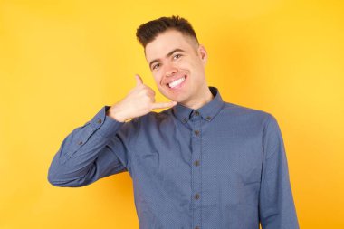 Yakışıklı genç iş adamı telefonla el ve parmaklarıyla telefonla konuşur gibi hareket ediyor. İletişim kavramları.