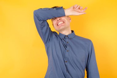 Yakışıklı genç iş adamı kollarıyla gözlerini kapatıyor neşeli ve komik gülümsüyor. Kör kavram.