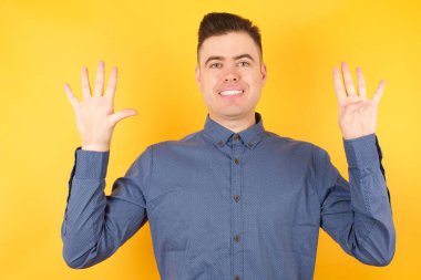 Yakışıklı genç işadamı dokuz numarayı gösterip işaret ederken kendinden emin ve mutlu gülümsüyor..