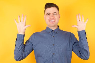 Yakışıklı genç işadamı on numarayı gösterip işaret ederken kendinden emin ve mutlu bir şekilde gülümsüyor..