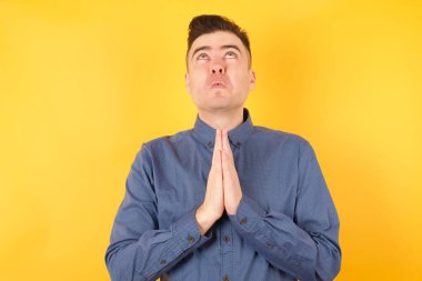 Yakışıklı genç işadamı elleri bağlı yalvarıyor ve dua ediyor. Yüzünde umut ifadesi var. Çok duygusal ve endişeli. Soruyorum.