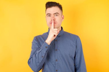 Yakışıklı genç işadamı parmakları dudaklarında sessiz olmak istiyor. Sessizlik ve gizli konsept.