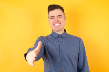 Yakışıklı genç iş adamı selamlama ve hoş geldin demek için el sıkışmayı teklif ediyor. Başarılı bir iş..