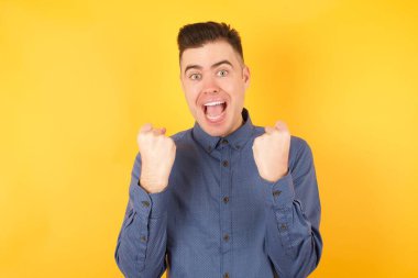 Yakışıklı genç işadamı, kollarını kaldırıp gözlerini açarak başarının şaşkınlığını ve şaşkınlığını yaşadı. Kazanan konsept.