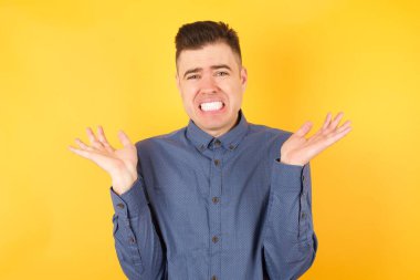 Yakışıklı genç işadamı şaşkınlık içinde hareketler yapıyor, tatminsizlikle kaşlarını çatıyor. 