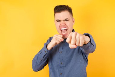 Yakışıklı genç işadamı yumruğuyla havayı yumrukluyor ve kameraya özgüvenle bakıyor. Kadın mücadelesi, savaşçı ruhu. Stüdyo çekimi  