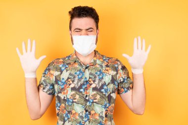 Koruyucu maskeli yakışıklı genç adam avuçlarını zevkle kaldırıyor, günlük kırmızı gömlekler giyiyor, aşırı seviniyor, arkadaşı tarafından eğlendiriliyor. İnsanlar ve duygular.