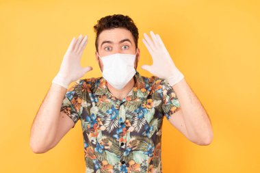 Koruyucu maskeli yakışıklı genç adam ellerini başının üstünde tutuyor, çenesi düşük. Omg kavramı