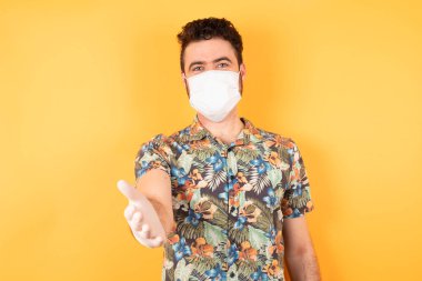 Koruyucu maskeli genç yakışıklı adam yardım ve kabullenme veriyor..