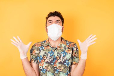 Koruyucu maskeli yakışıklı genç adam deli gibi bağırıyor, bağırıyor ve agresif bir ifadeyle kollarını kaldırıyor. Hayal kırıklığı konsepti.