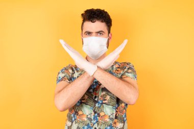Koruyucu maskeli yakışıklı genç adam kollarını kavuşturuyor.