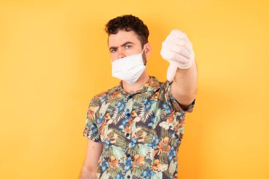 Kısa saçlı genç esmer adam kızgın, sinirli, hayal kırıklığına uğramış ya da canı sıkkın beyaz duvara ciddi ciddi bakıyor.