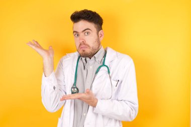 Yakışıklı doktor iki eliyle tuhaf bir şey gösteriyor. Reklam kavramı.
