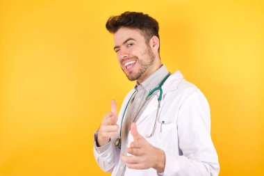 Hey sen, bang. Neşeli ve karizmatik yakışıklı beyaz doktor kameraya mutlu ve küstahça poz vererek göz kırpıyor. 