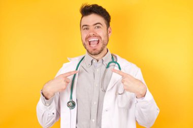 Neşeli doktor üniformasını göstererek harika bir günün ardından iyi bir ruh hali içinde olduğunu gösteren yatay bir fotoğraf..