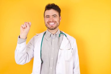 Sarı arka planda tıbbi üniforma giyen yakışıklı genç doktor Çince işaret diliyle 