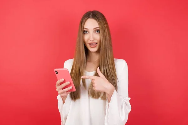 Portrét Mladé Krásné Ženy Chytrým Telefonem Pózování Červeném Pozadí Studia — Stock fotografie