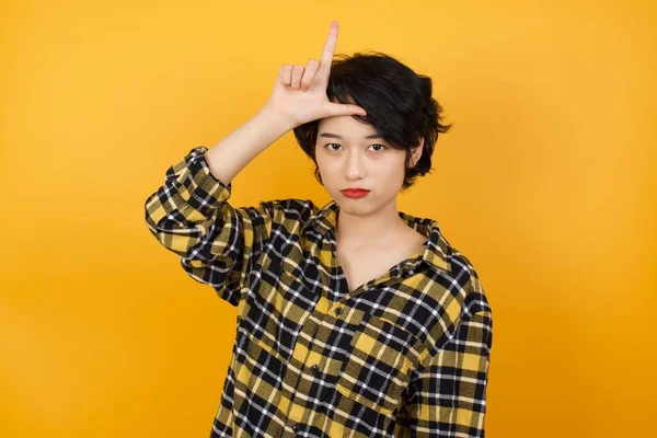 Güzel genç bir kadın, alnında parmakları olan insanlarla dalga geçiyor. Ezik jestler yapıyor, alay ediyor, hakaret ediyor..