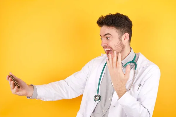 Upphetsad Stilig Läkare Man Bär Medicinsk Uniform Visar Mobiltelefon Med — Stockfoto