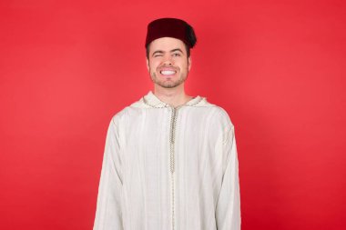 Stüdyoda, fes takmış yakışıklı bir gencin kameraya şakacı bir şekilde göz kırpıp seninle flört ettiği yakın plan bir çekim. İnsan yüz ifadeleri ve duyguları