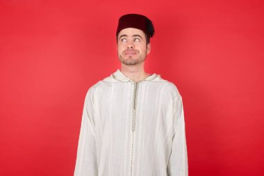 Neşeli, pozitif, yakışıklı, fes takan genç bir adamın boş boşluğa baktığı bir fotoğraf.  