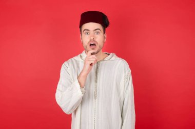 Geleneksel Türk şapkası fez giyen yakışıklı genç adam şaşkınlıktan ağzını açar ve ani haberlere tepki verir. İnsanlar ve yüz ifadeleri.