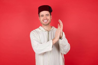 Geleneksel Türk şapkası takan yakışıklı genç adam alkışlıyor ve alkışlıyor. Mutlu ve neşeli, gururlu eller bir arada..