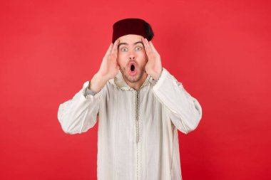 Geleneksel Türk şapkası takan yakışıklı genç adam ellerini başının üstünde tutuyor, çenesi düşük, harika bir ifadesi var. Omg kavramı