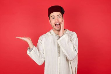 Geleneksel Türk şapkası takan yakışıklı genç adamın fotoğrafı. Avuç içi açık fes.  