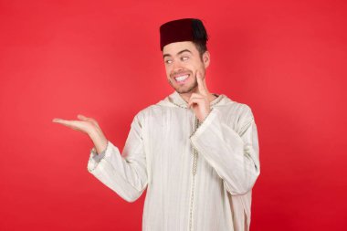 Geleneksel Türk şapkası takan yakışıklı genç adamın fotoğrafı. Avuç içi açık fes.  