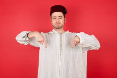 Geleneksel Türk şapkalı yakışıklı genç adam iki parmağıyla fotokopi alanını işaret ediyor. Reklam için yer. 