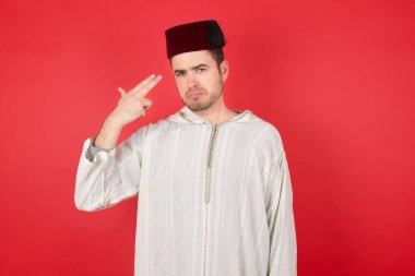 Fes takan mutsuz, yakışıklı genç adam silah atışı taklidi yapıyor, intihar hareketi yapıyor. 