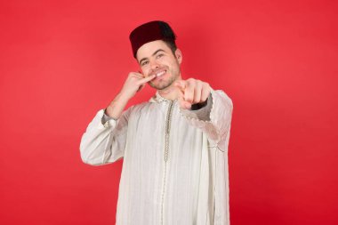 Fes takan yakışıklı genç bir adam kamerayı işaret ederek seni daha sonra arıyor. Telefonda düz renkli duvara karşı konuşuyor.