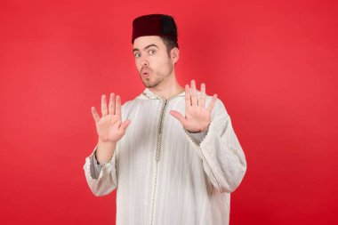 Geleneksel Türk şapkası takan yakışıklı genç adam reddediyor ve iğrenç bir ifadeyle reddediyor. Dur ve yasakla.