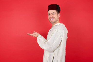 Geleneksel Türk şapkası takan yakışıklı genç adam avuçlarını açmış, fotokopi alanını gösteriyor, reklam sunuyor.  