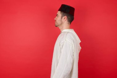 Geleneksel Türk şapkası takan yakışıklı bir genç adam. Taraf arıyor, rahat bir poz veriyor. Kendine güvenen bir gülümsemesi var..