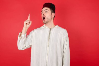 Geleneksel Türk şapkası giyen yakışıklı genç adam fez başarılı bir fikir işaret ediyor. Heyecanlı ve mutlu. Bir numara..