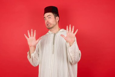 Geleneksel Türk şapkası takan yakışıklı genç adam korku ifadesinden korkuyor ve dehşete düşüyor. El kol hareketi yapmayı kes, şok içinde bağır. Panik konsepti.