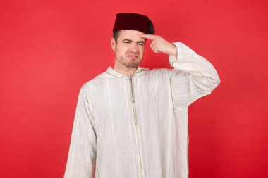 Geleneksel Türk şapkası takan yakışıklı genç adam alnındaki sivilceden memnun değil, siyah nokta enfeksiyonu. Cilt bakımı kavramı.