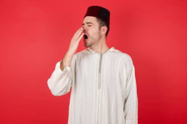 Geleneksel Türk şapkası giyen yakışıklı genç adam Fez bütün gününü işte geçirdikten sonra esniyor..