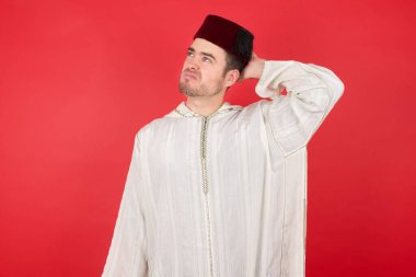 Geleneksel Türk şapkası giyen yakışıklı genç adamın kafası karışmış ve soru sormayı merak ediyor. Şüpheyle kararsız, kafa kafaya düşünerek. Düşünceli kavram.